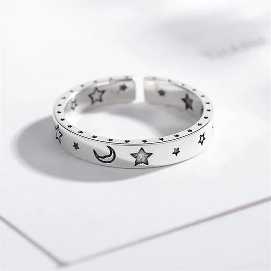 Silver ring with star and moon designs on a white background