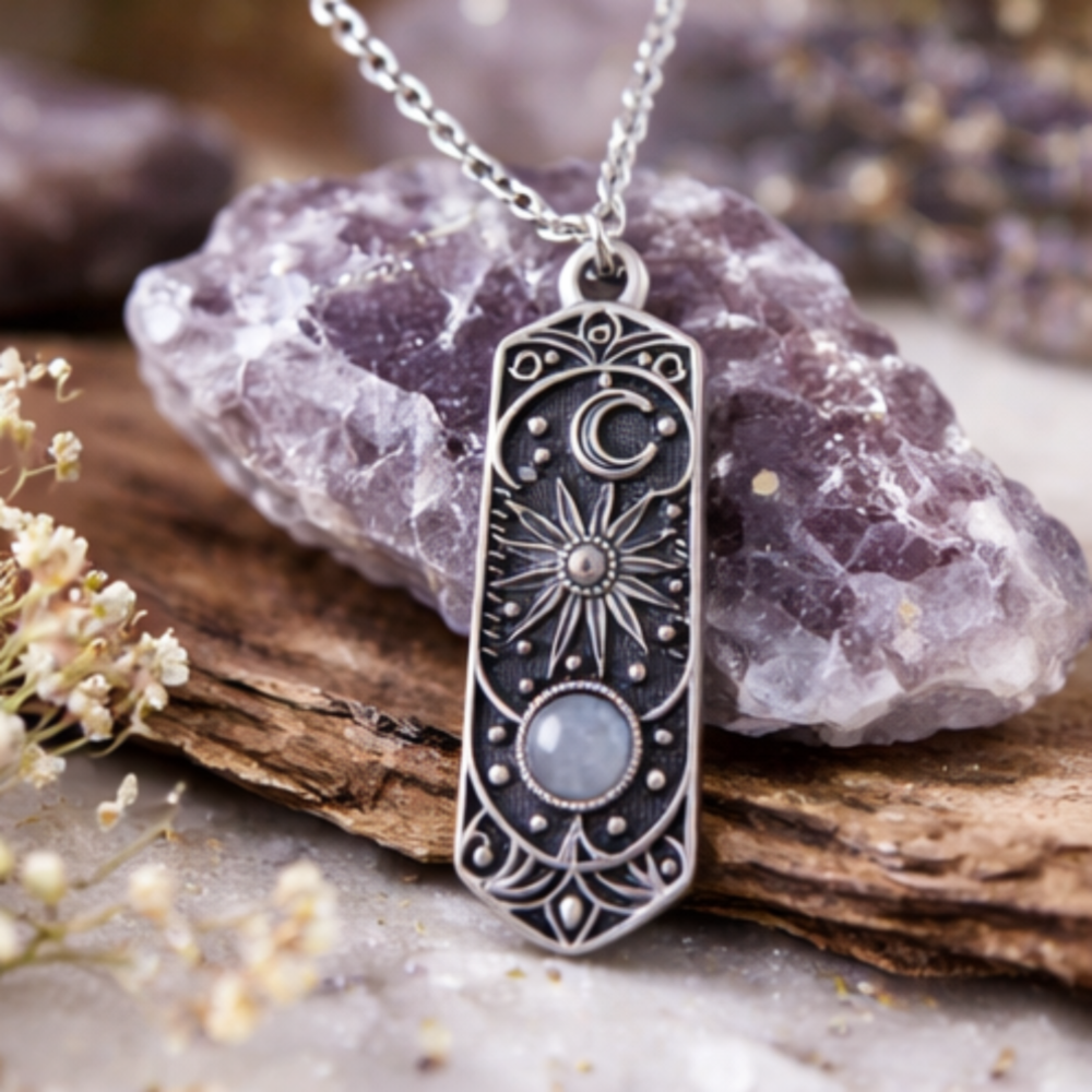 Silver pendant necklace with intricate designs on a stone surface