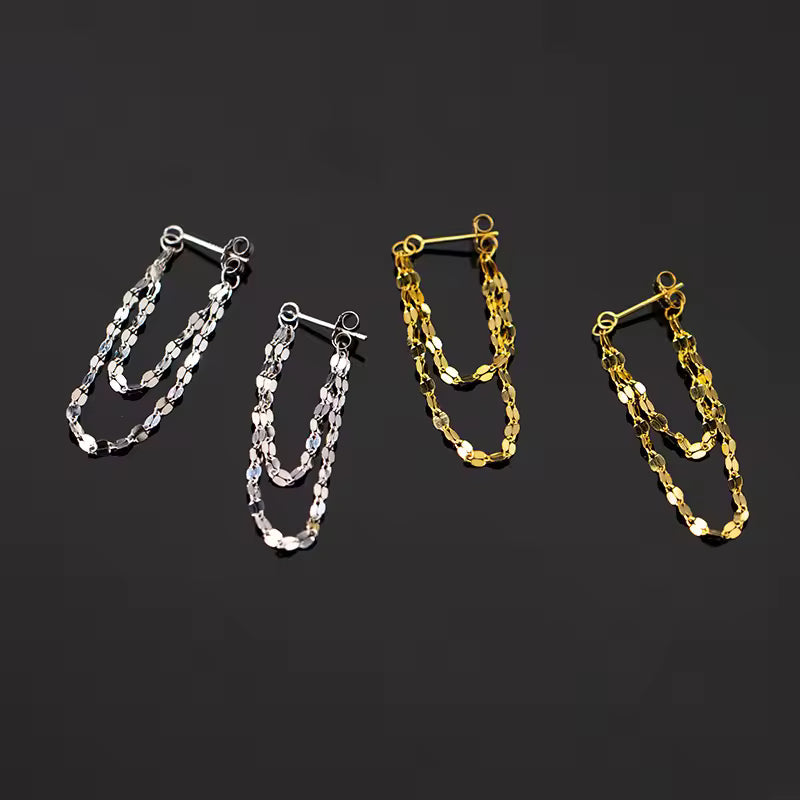 Two pairs of chain earrings, one silver and one gold, on a black background.