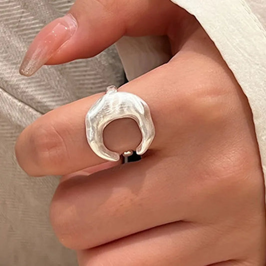 Silver ring on a person's finger with a neutral background