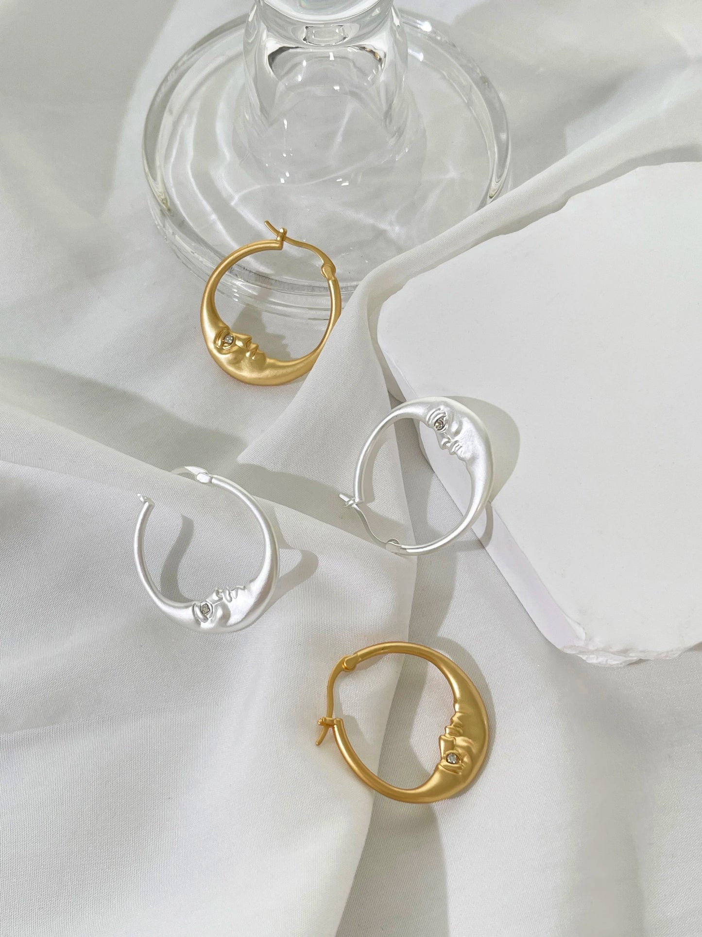 hoop earrings in gold and silver on a white fabric background