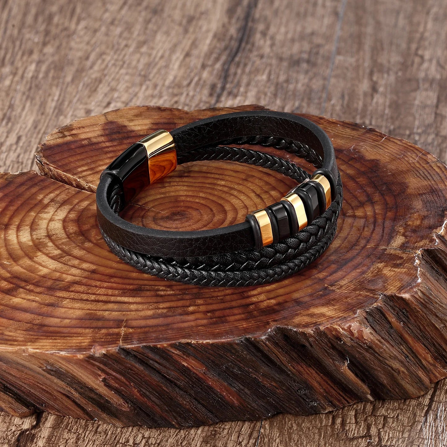 Black braided leather bracelet with gold accents on a wooden surface