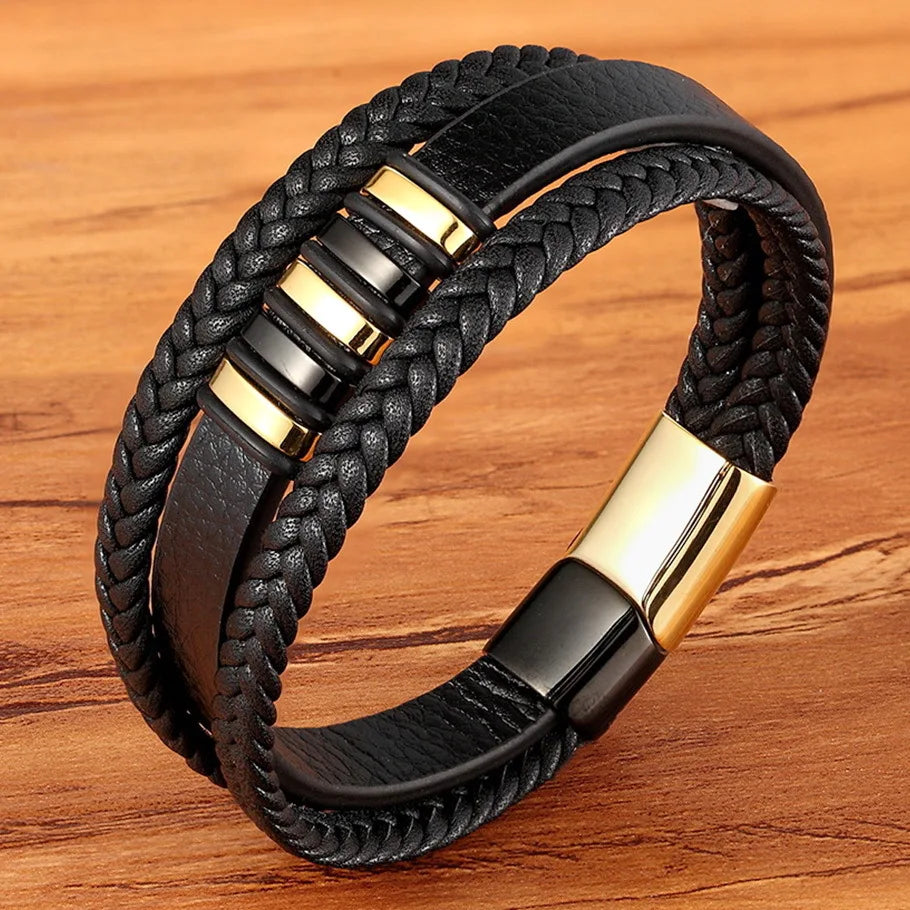 Black braided leather bracelet with gold accents on a wooden surface