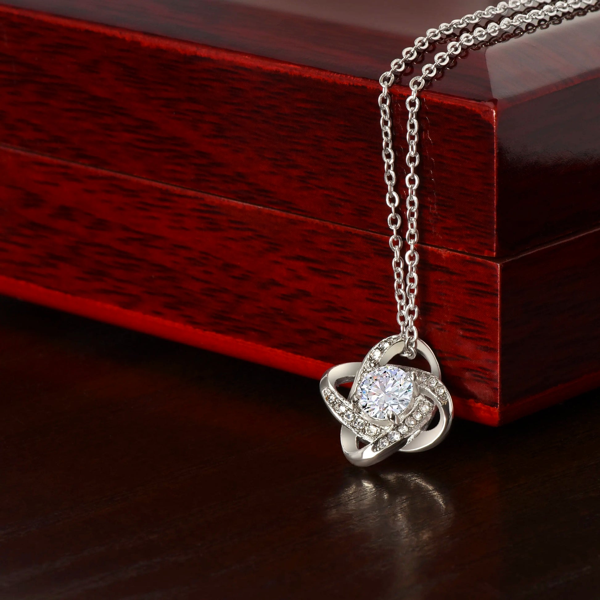 Silver necklace with a heart-shaped pendant on a wooden surface