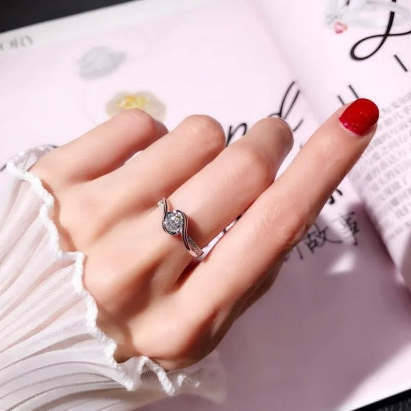 Hand wearing a silver ring with a diamond on a white background