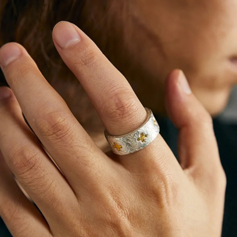 Close-up of a hand wearing a silver ring with gold crosses.