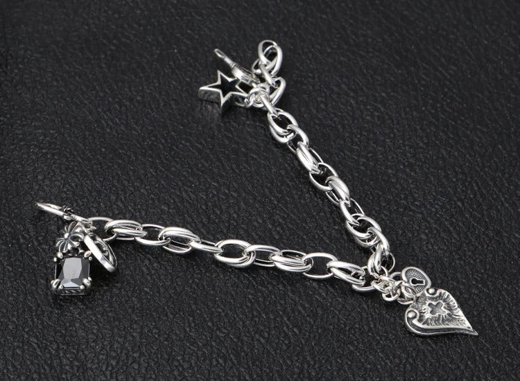 Silver chain bracelet with various charms on a black background