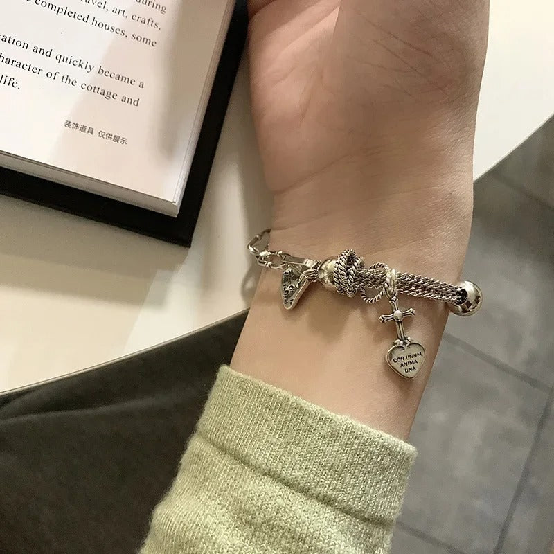 Close-up of a wrist wearing a detailed bracelet with charms, against a blurred background.