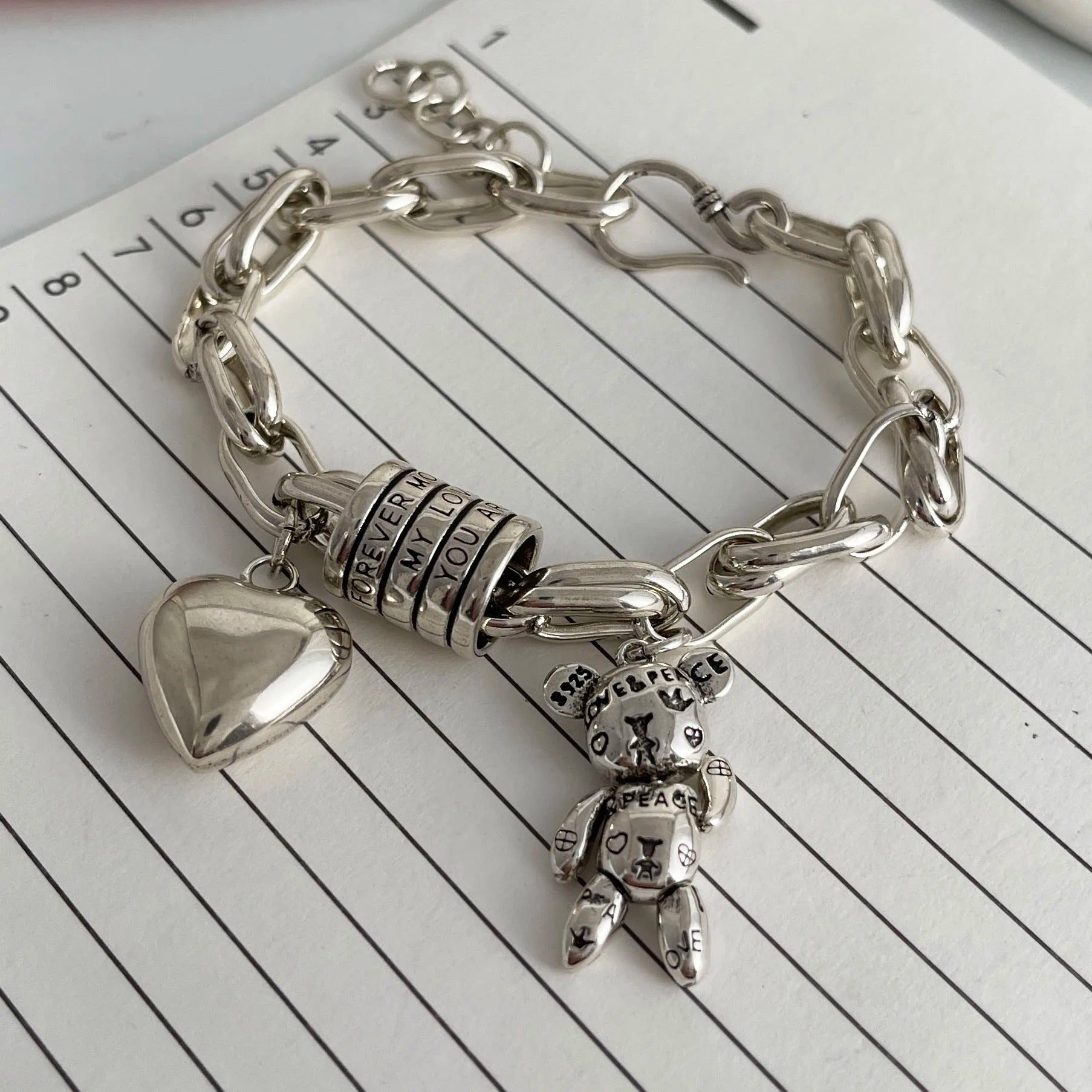 Silver chain bracelet with charms on a lined paper background