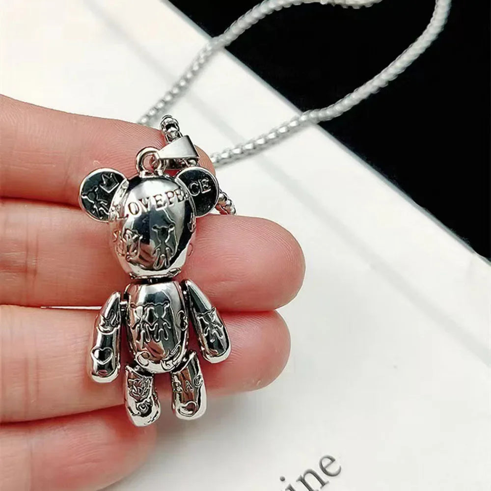 A silver bear-shaped pendant necklace held in a person's hand, featuring engraved details and a matching silver chain against a white and black background.
