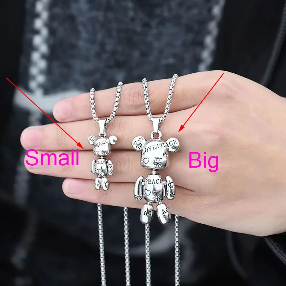 A hand holding two silver bear pendants on chains, labeled 'Small' and 'Big' with red arrows and pink text. The pendants have engraved words like 'LOVE', 'LIGHT', and 'PEACE'.
