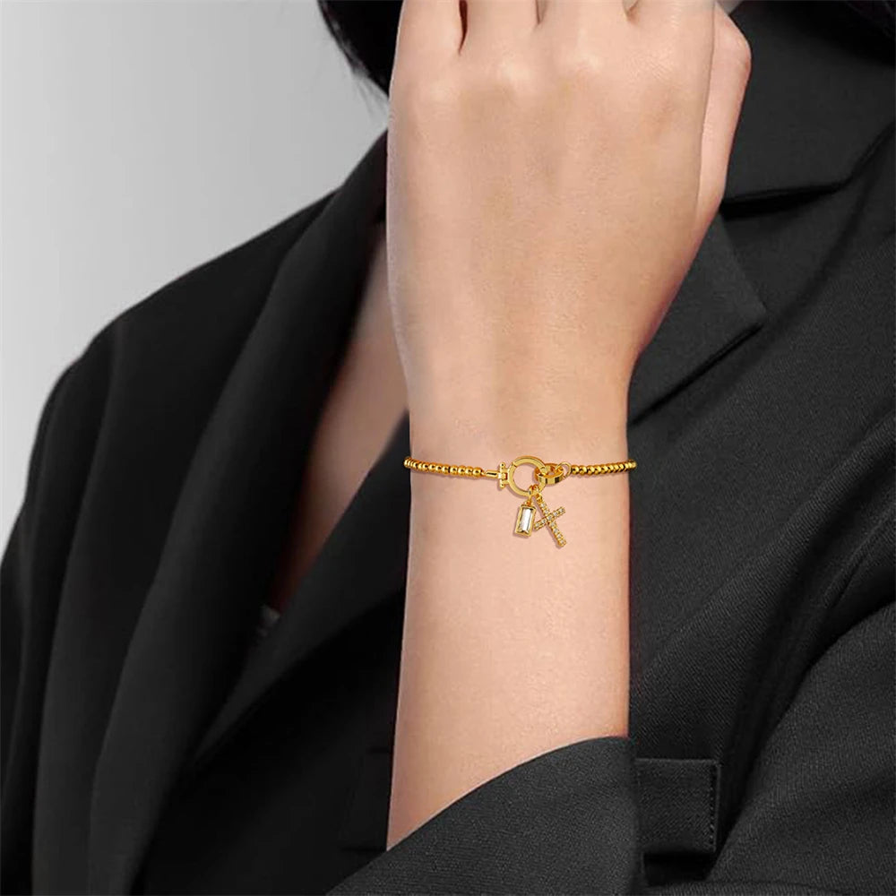 Gold bracelet with charms on a person's wrist against a black background