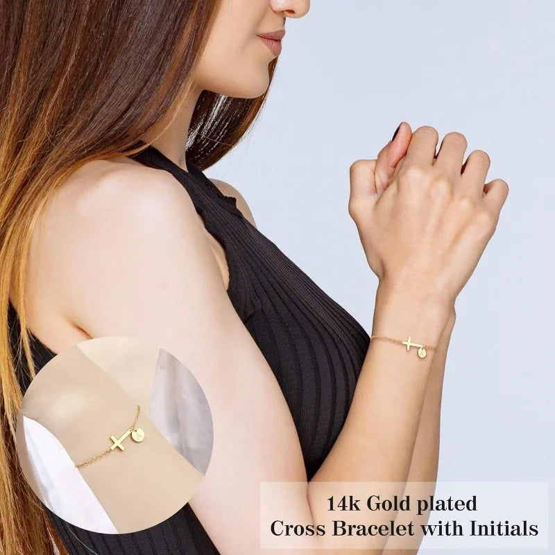 Woman wearing a 14k gold-plated cross bracelet with initials on a plain background