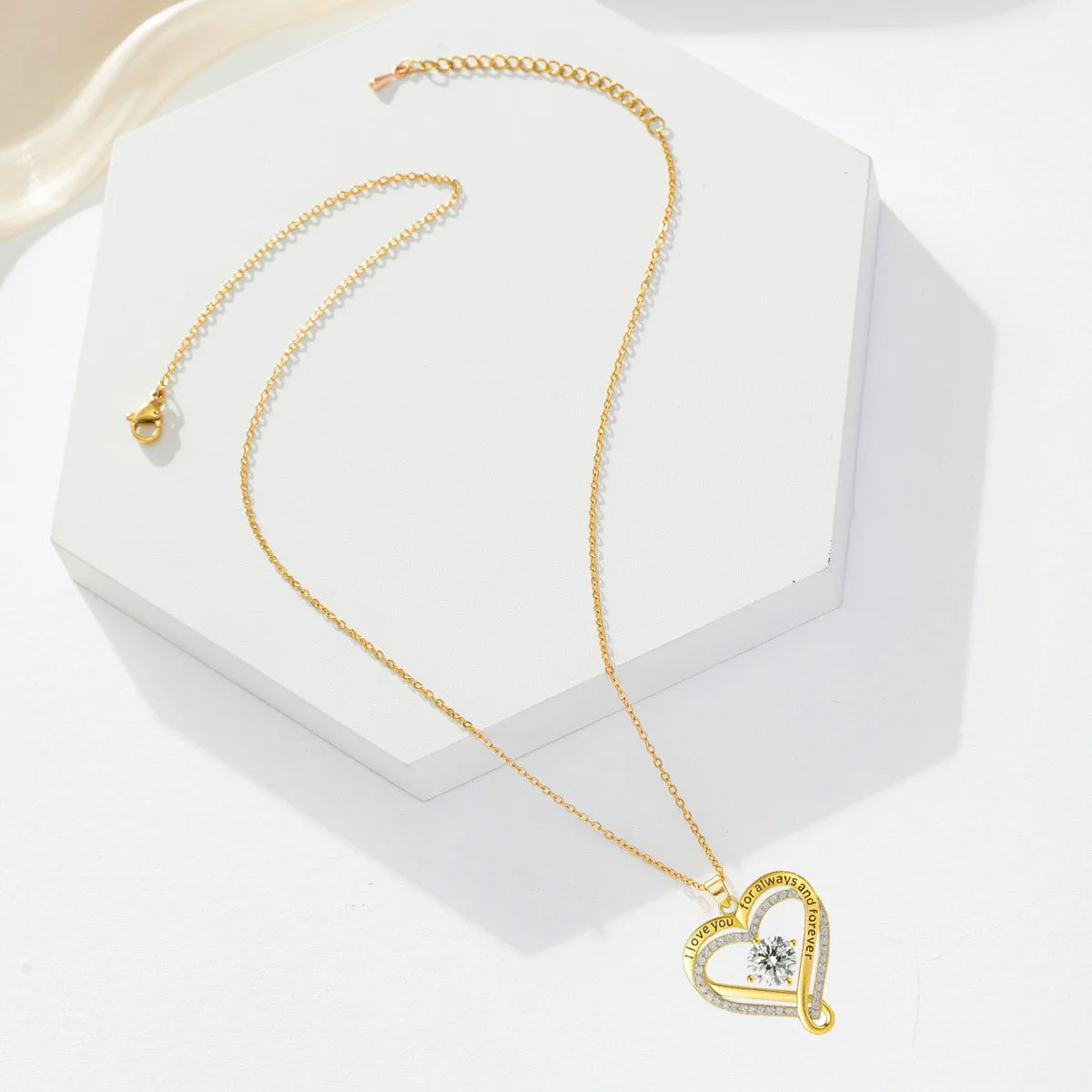 Gold necklace with a heart-shaped pendant on a white stand