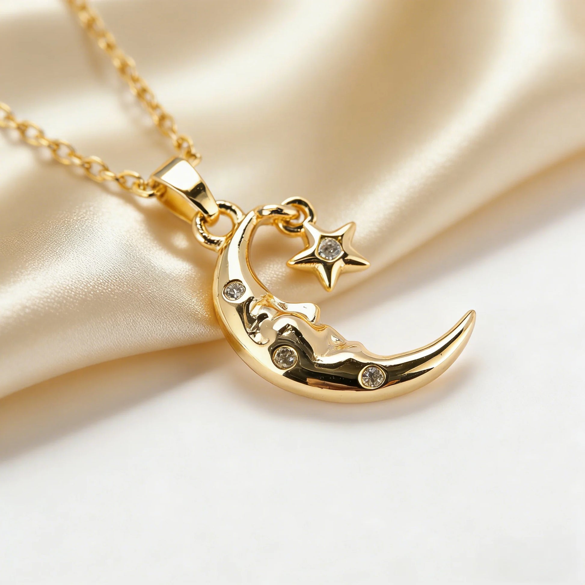 Gold necklace with a crescent moon and star pendant on a satin surface