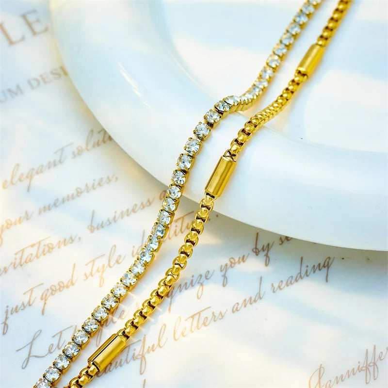 Gold chain necklace with crystals on a textured surface
