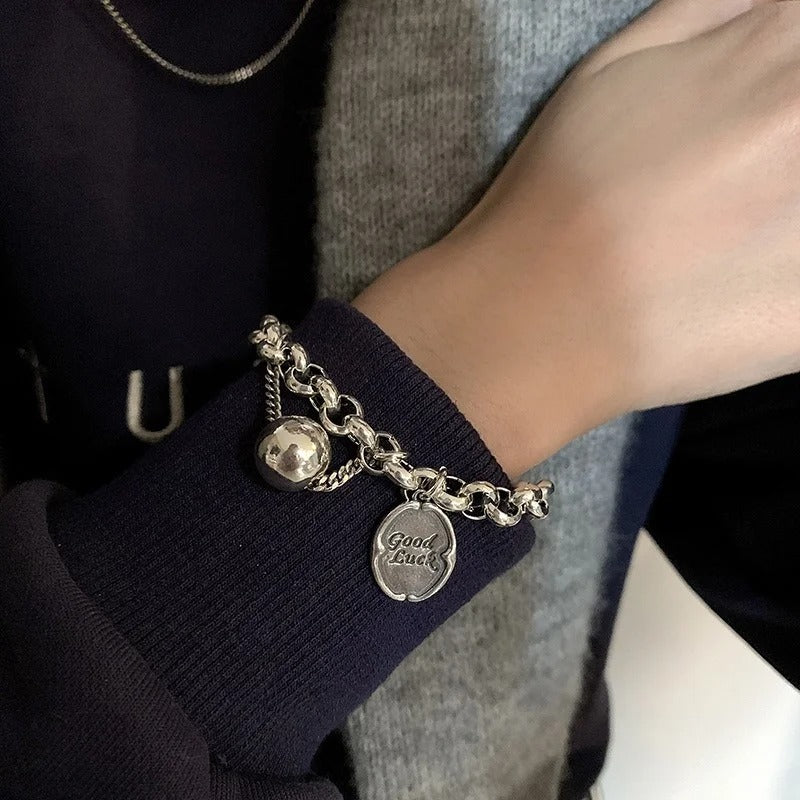 Bracelet with charms on a wrist, wearing a dark blue sleeve.