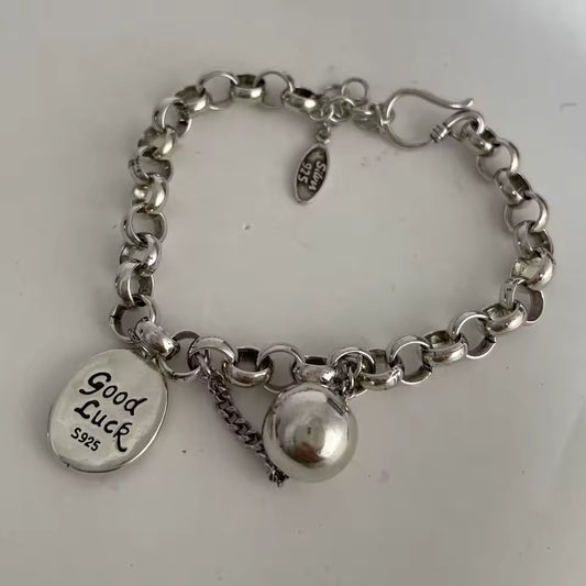 Silver bracelet with 'Good Luck' charm on a white background