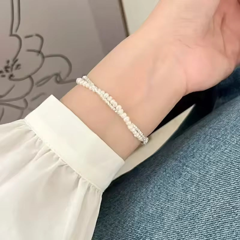 Close-up of a wrist wearing a pearl bracelet with a neutral background