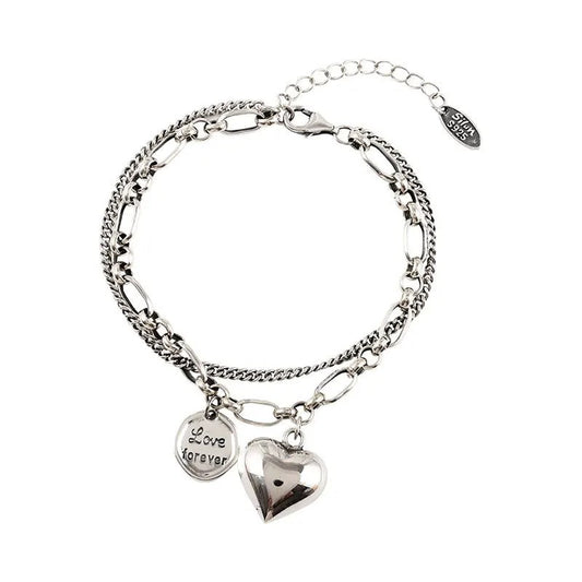 Silver bracelet with heart-shaped charm and 'Love forever' tag on a white background