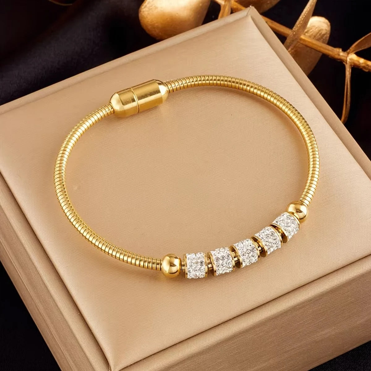 Gold bracelet with diamond accents on a beige box