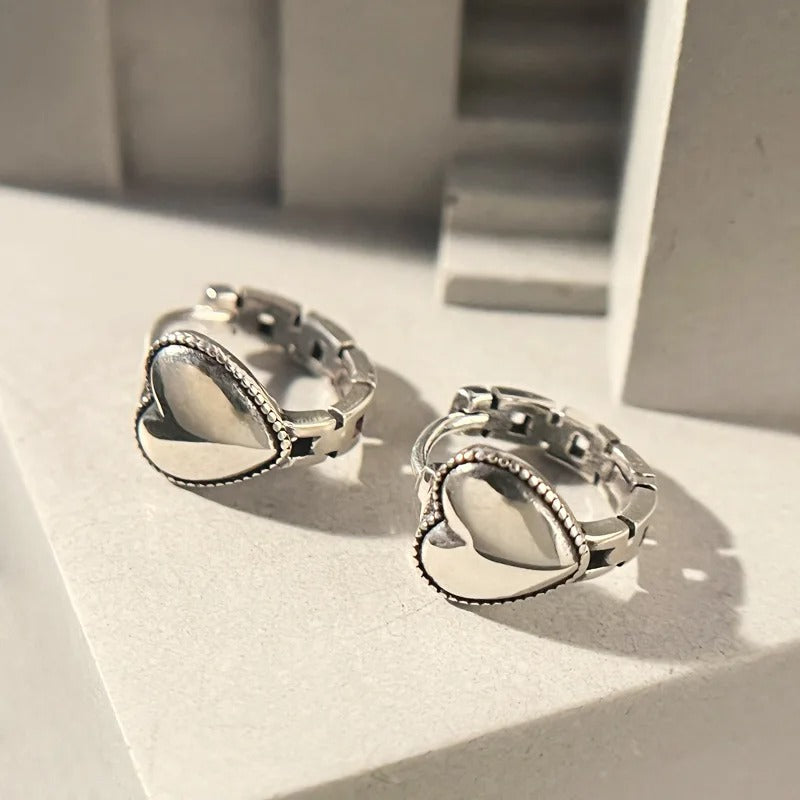 Pair of silver stud earrings on a light surface with a neutral background