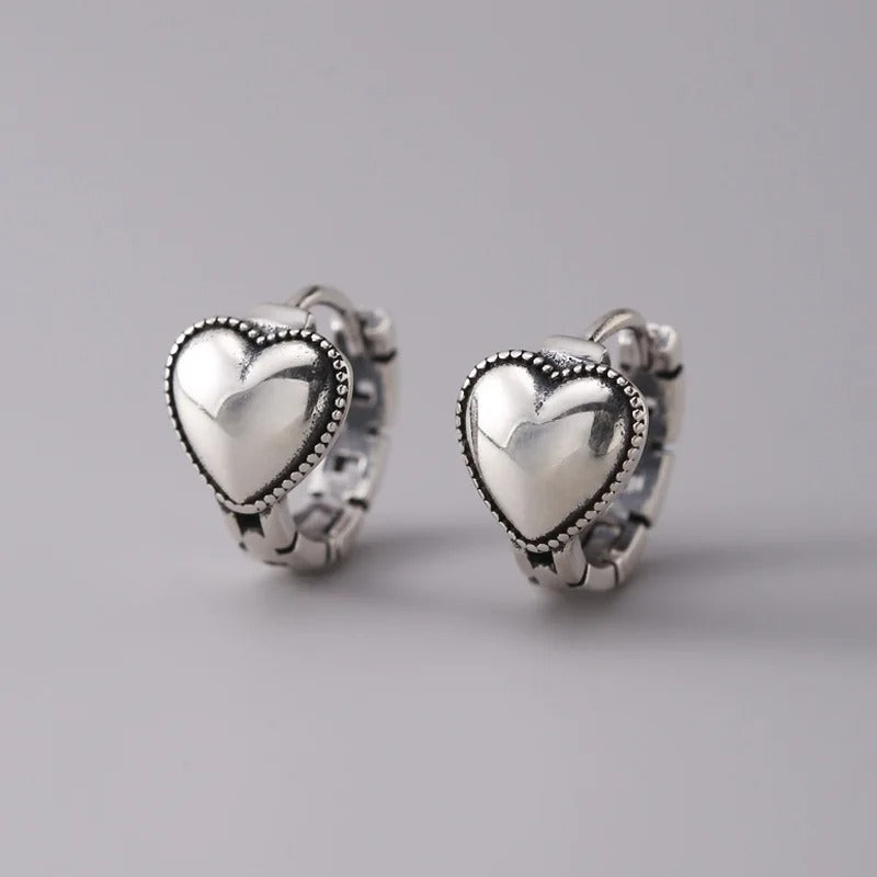 Heart-shaped silver earrings on a gray background