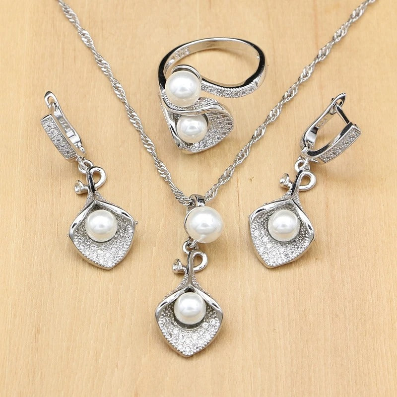 Silver jewelry set with pearls on a wooden surface