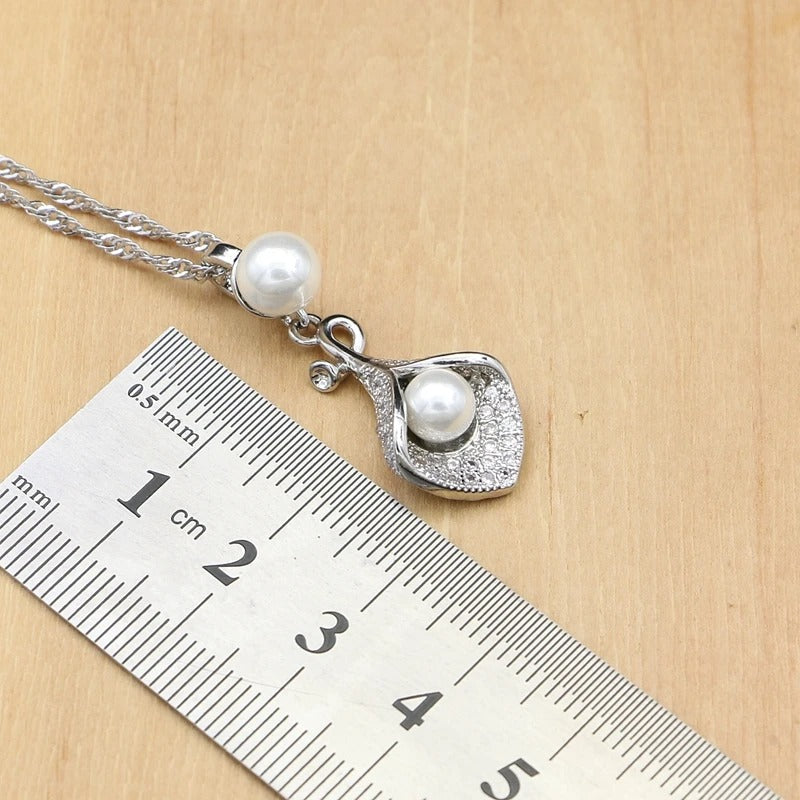 Necklace with a pendant featuring pearls on a wooden surface with a ruler for scale.
