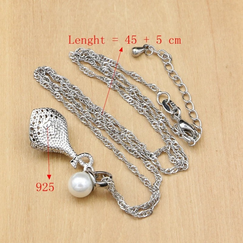 Silver necklace with a pearl pendant on a wooden surface, showing length measurement.