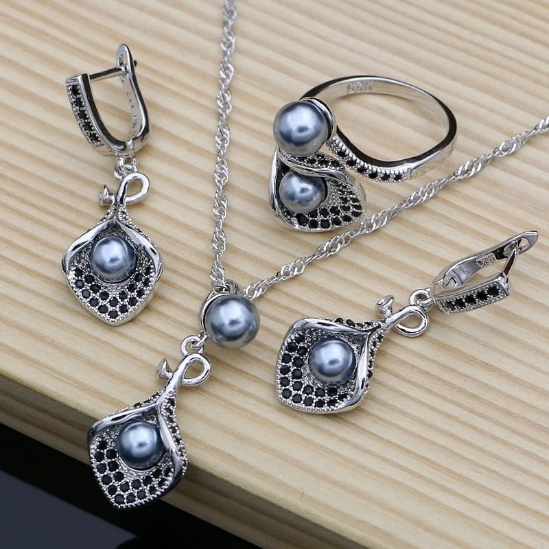 Silver jewelry set with pendants, necklace, and ring on a wooden surface