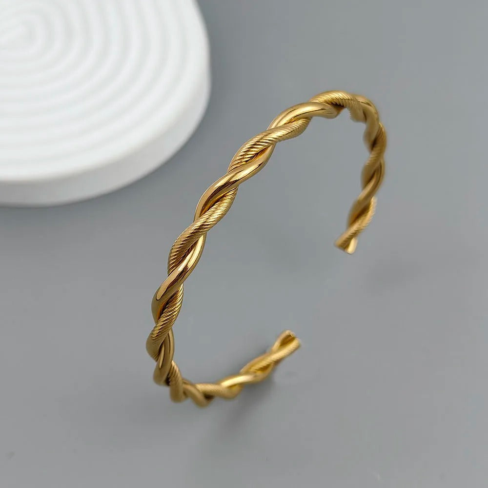 Gold twisted bangle on a gray background