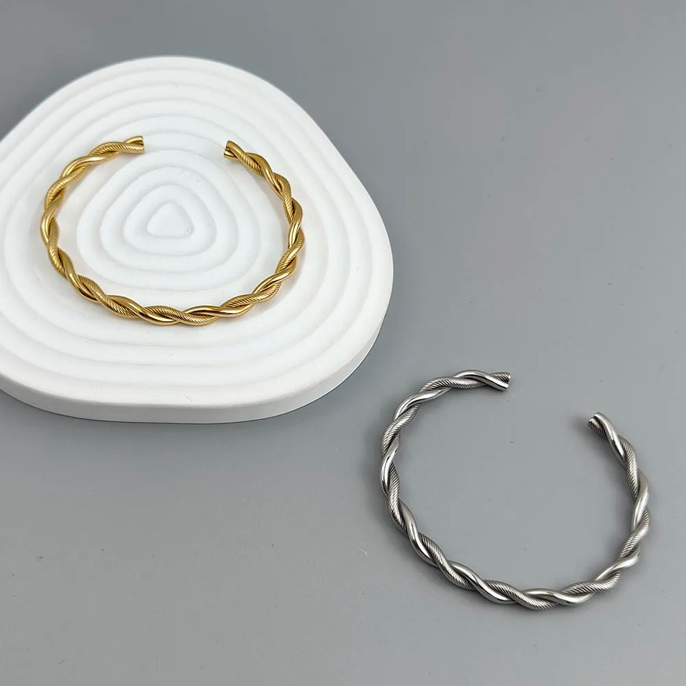 Gold and silver twisted bangles on a gray background