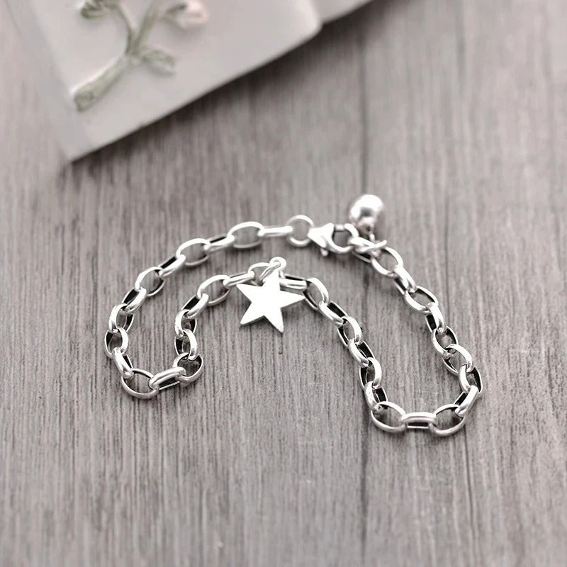 Silver chain bracelet with a star charm on a wooden surface
