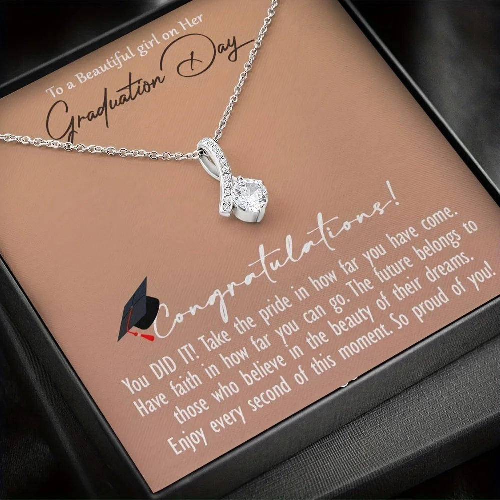 Silver necklace with a heart pendant on a graduation-themed card.