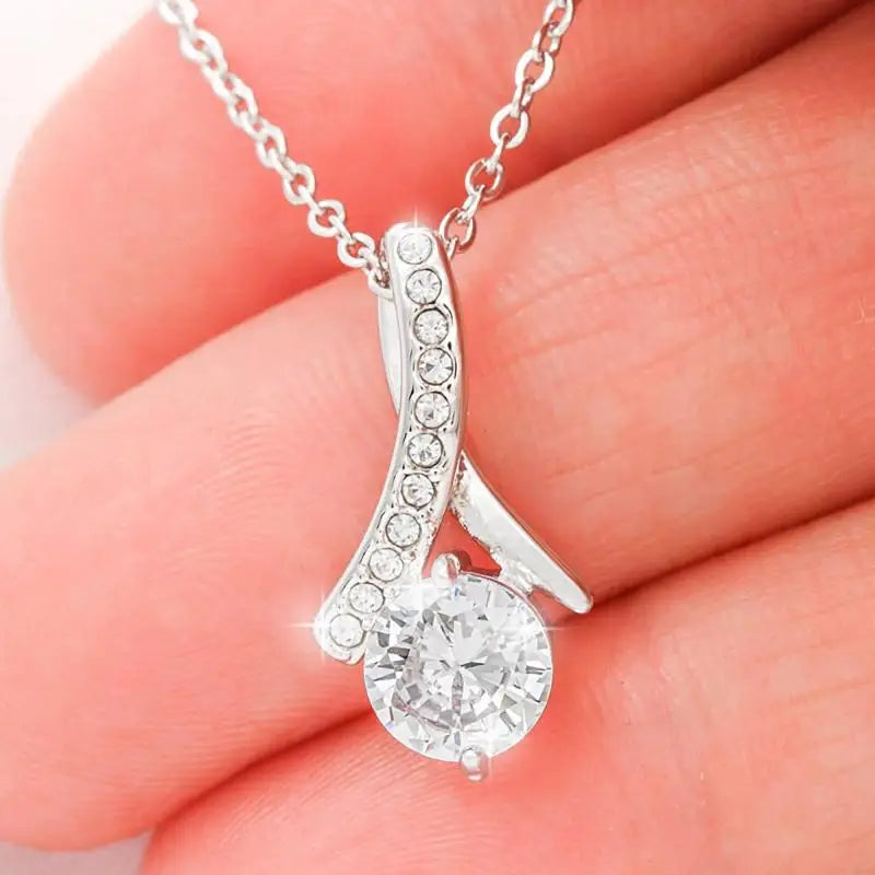 Silver necklace with a diamond pendant held between fingers