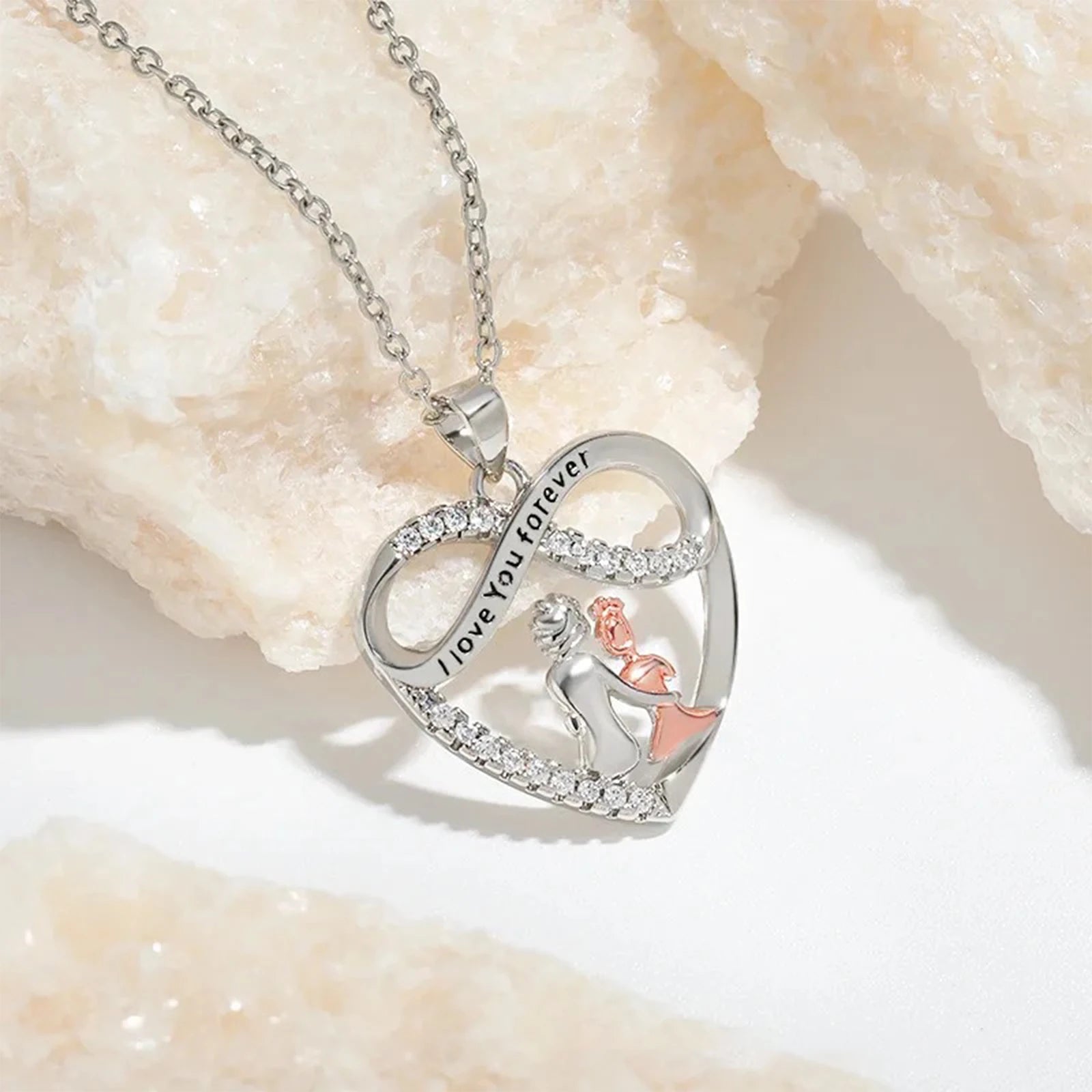 Heart-shaped silver necklace with 'I love you forever' engraving on a light background