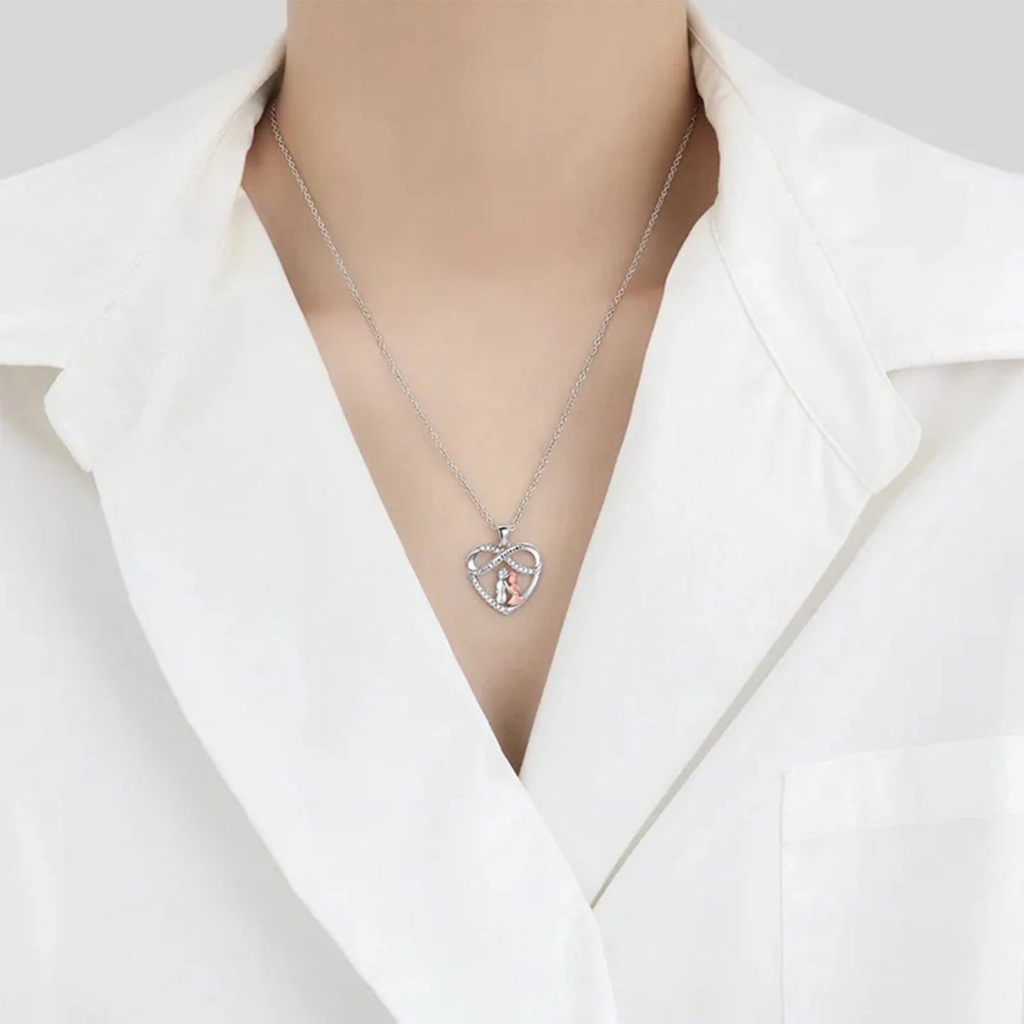 Necklace with a heart-shaped pendant worn by a person in a white blazer.