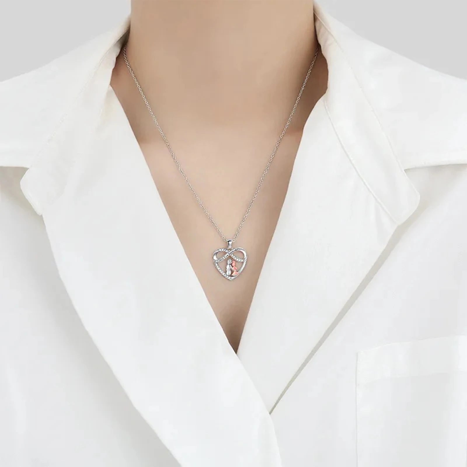 Necklace with a heart-shaped pendant worn by a person in a white blazer.