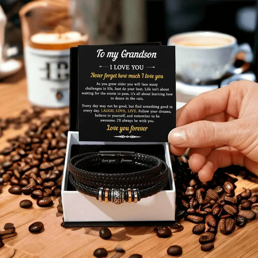 Person holding a card with a message and two leather bracelets on a wooden surface with coffee beans and a cup in the background.
