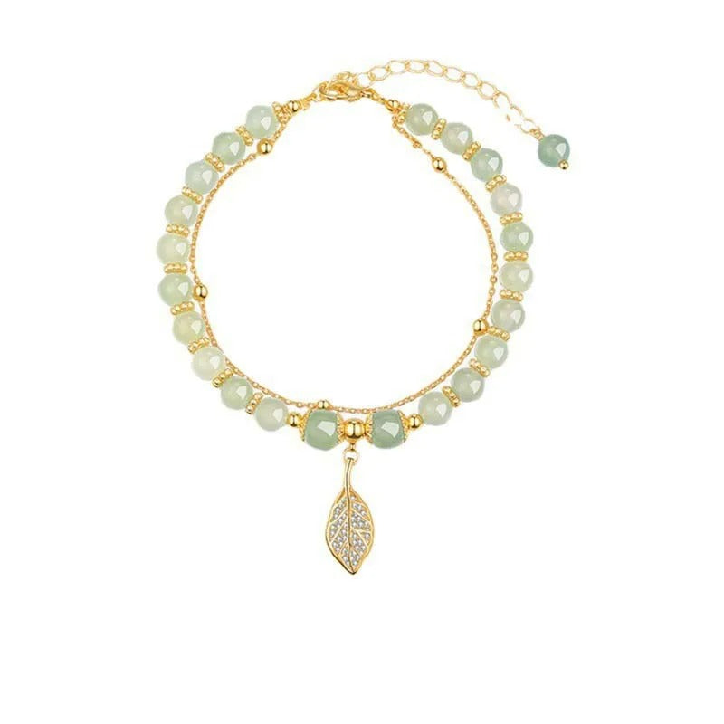 Bracelet with green beads and gold accents on a white background