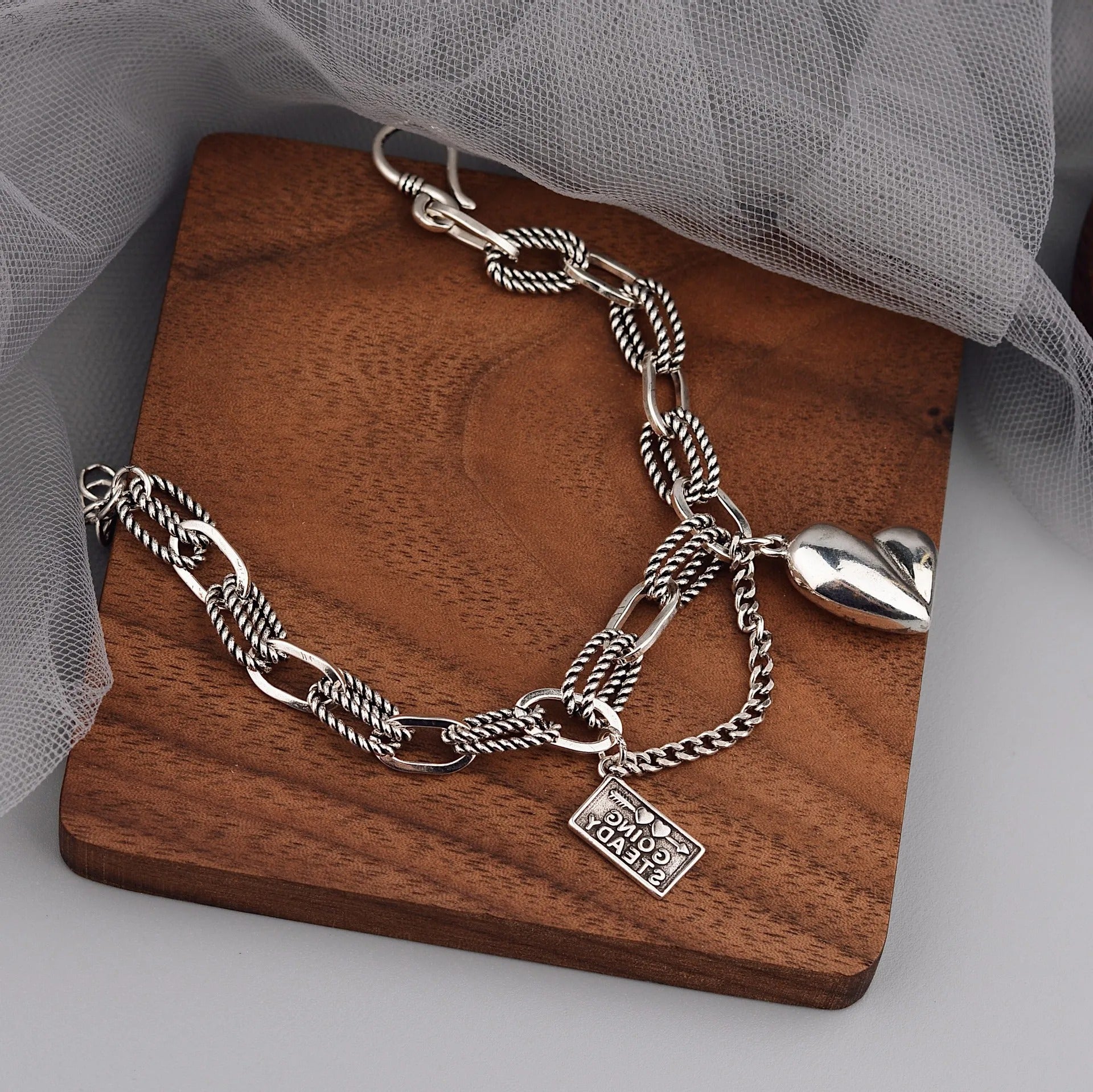 Silver chain necklace with heart charm on a wooden stand