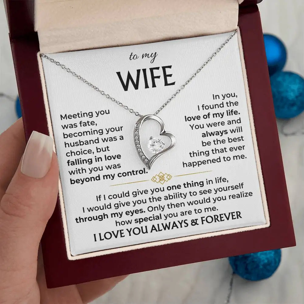 Heart-shaped necklace with sentimental card for a wife, held by a hand.