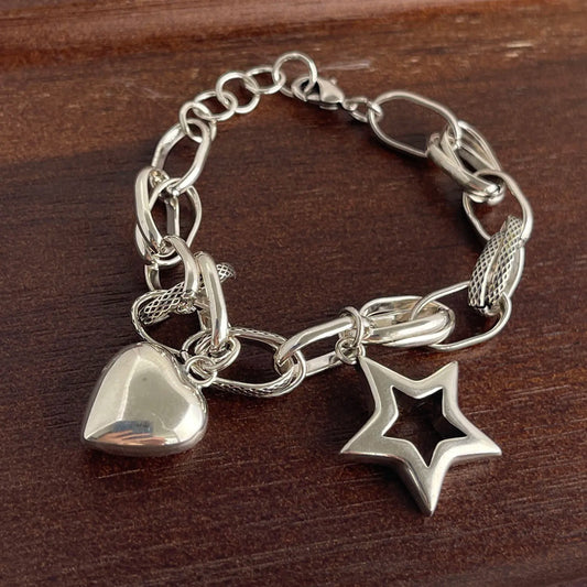 Silver chain bracelet with heart and star charms on a wooden surface