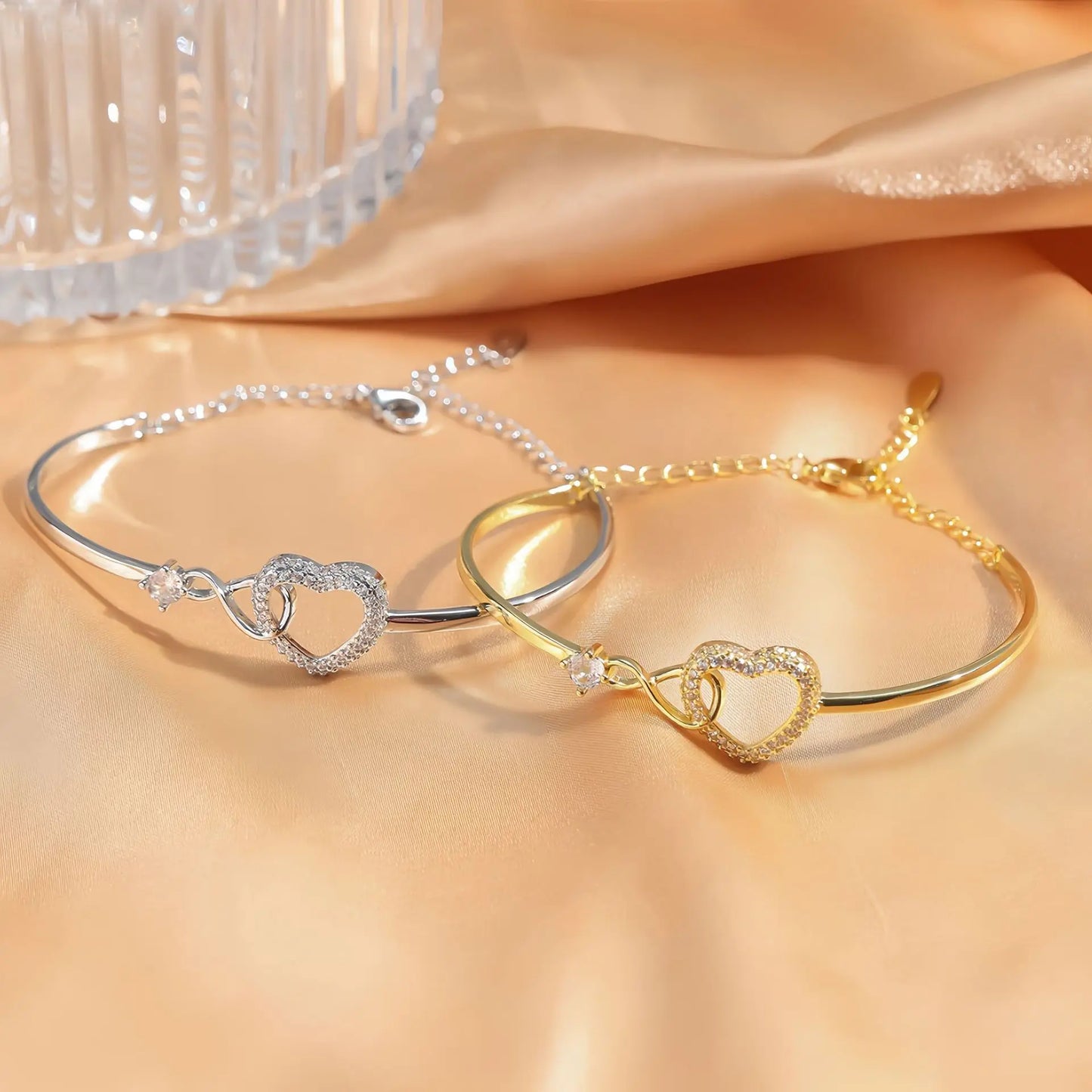 Gold and silver heart-shaped bracelets on a soft fabric background