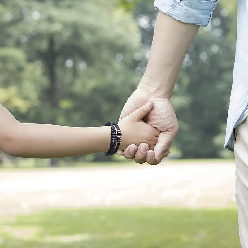 Two people holding hands with a blurred green outdoor background