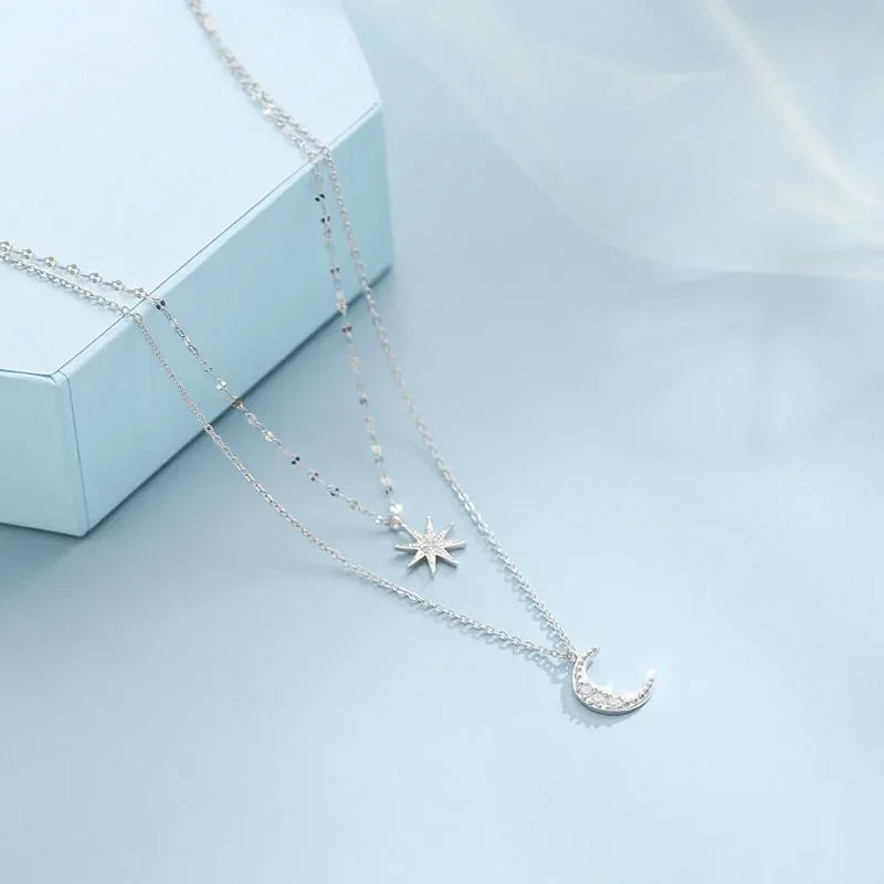 Silver necklace with star and moon pendants on a light blue background