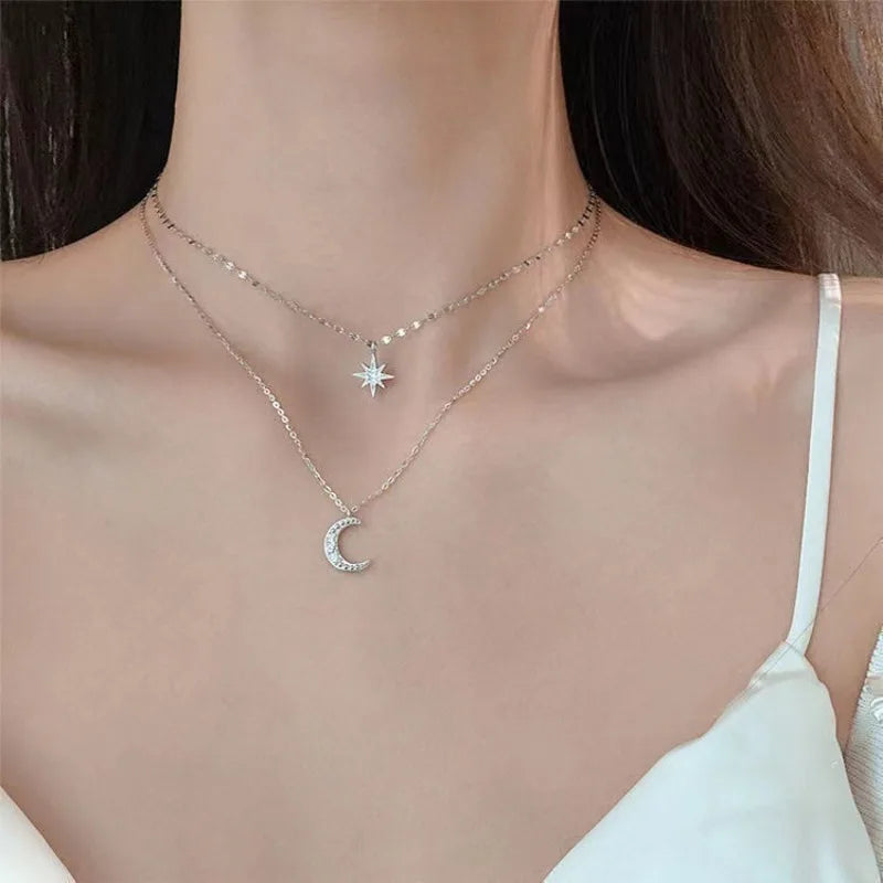 Necklace with star and moon pendants on a person wearing a white top.