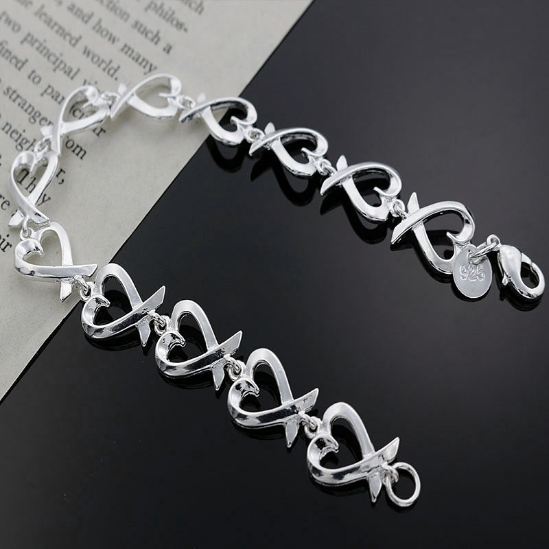 Silver bracelet with heart designs on a black and white background