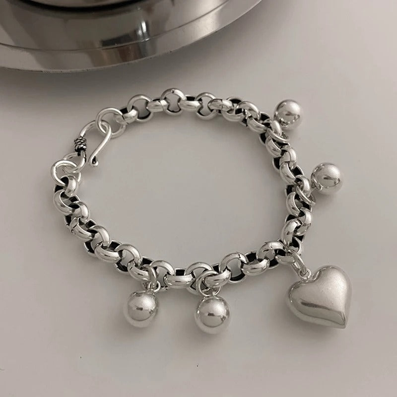 Silver bracelet with heart charm on a light gray background